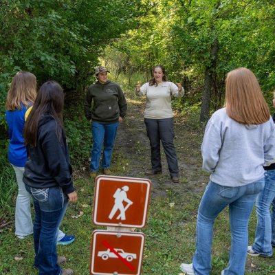 Students and instructor standing in a circle on a walking trail.