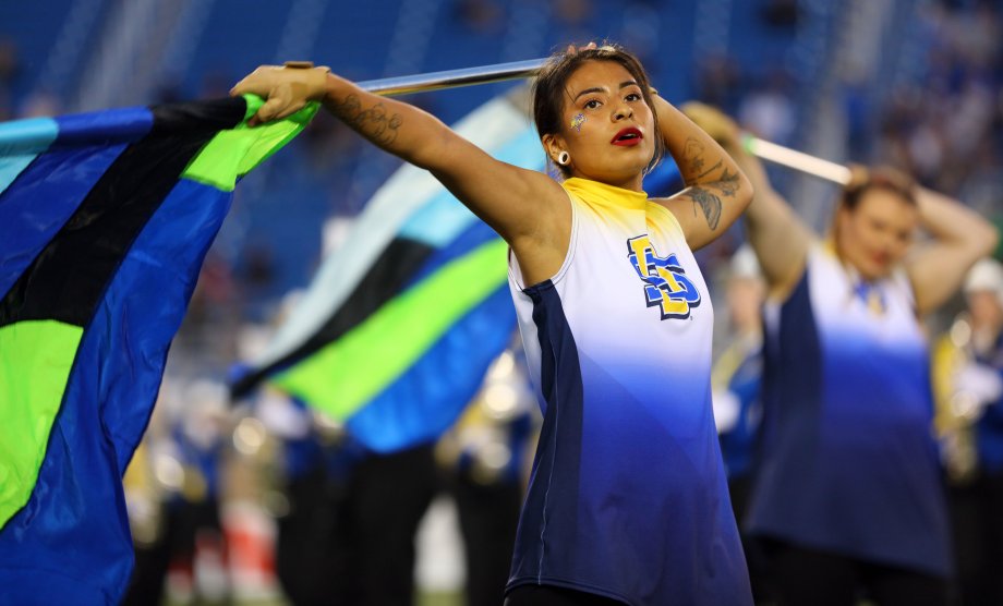 A color guard student holding a flag to her left.