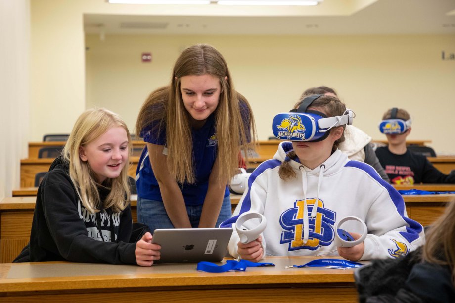A SDSU student showing middle schools a VR device.