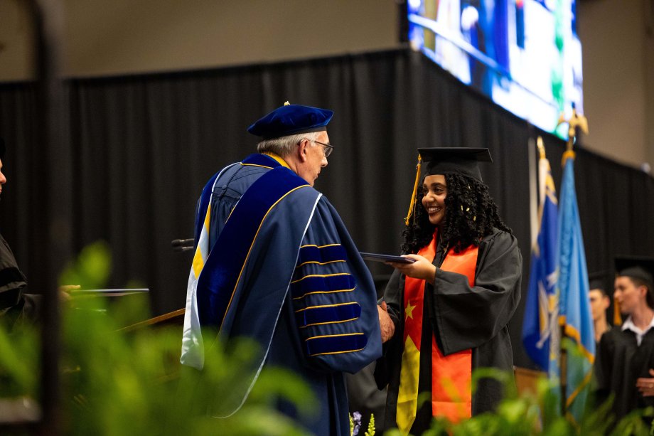 President Barry Dunn handing a diploma to a graduate at commencement ceremonies.