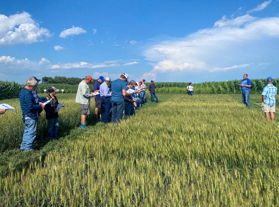 A group of adults standing in a field and listening to an instructor speak.