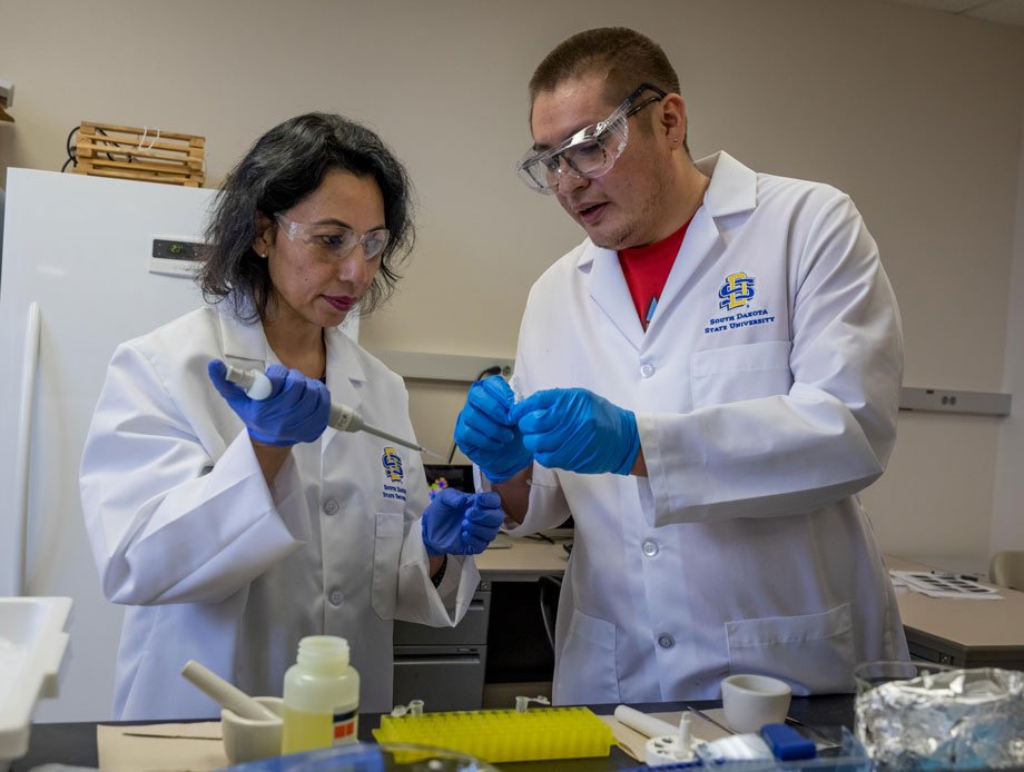 Bijaya Pradhan, left , and Dillon Nelson add enzyme to plastic cap container